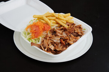 A plate of food with a piece of meat and a side of fries. The meat is cut into small pieces and is served on a white plate