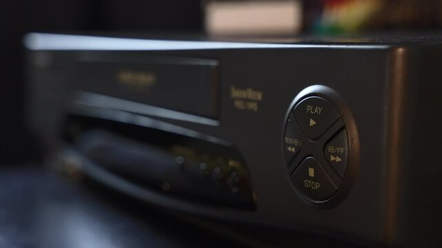 Hand Inserting VHS Tape Into Retro Video Player and Pressing Play