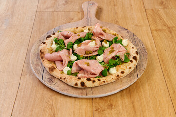 A delicious ham and cheese pizza sits on a wooden board, ready to be enjoyed. The crust is crispy and golden brown, and the toppings are fresh and flavorful. The cheese is melted and bubbly