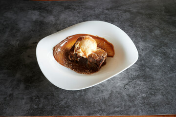 A dessert with ice cream on top. The dessert is brown and has a brown sauce on it