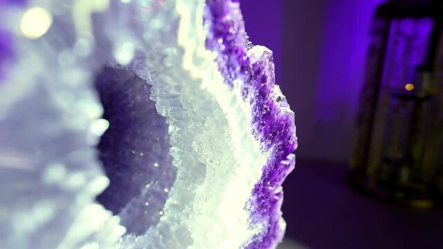 Detailed shot of a purple and white geode formation illuminated by a soft light showcasing natural crystalline patterns and textures.
