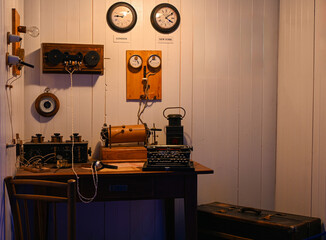 Old radio communication equipment, typewriter, headphones, and clocks showing london and new york...