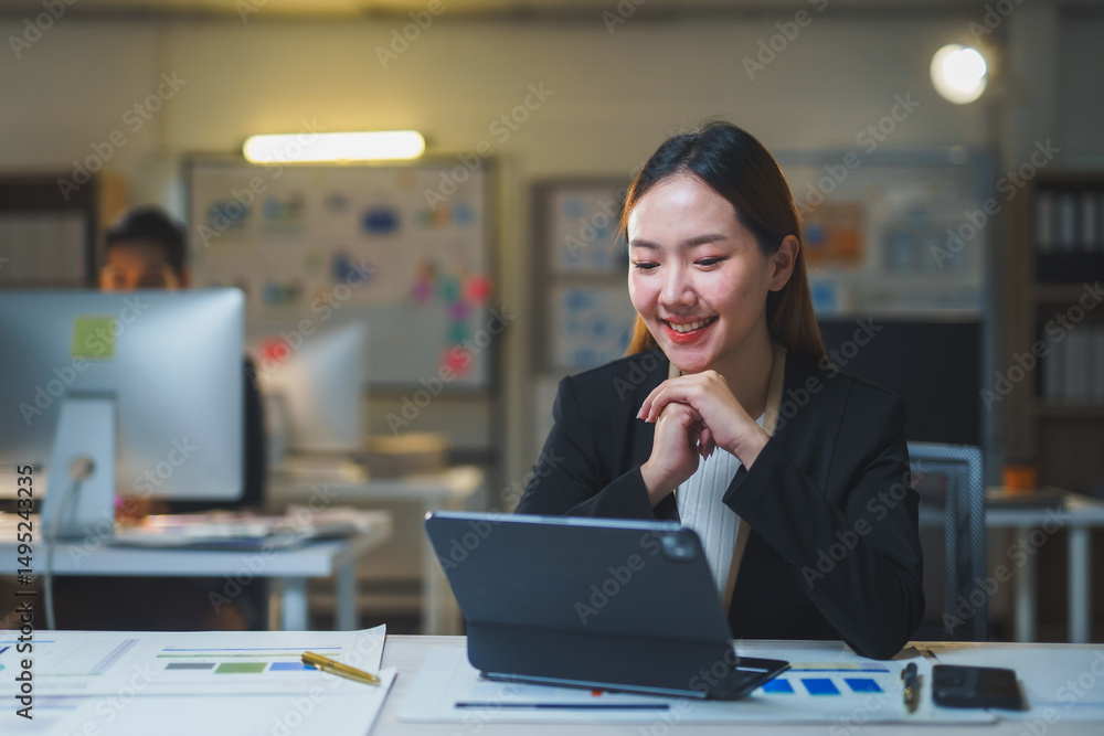 Poster young manager working late in the office, using a tablet to analyze graphs and data, focused on achi
