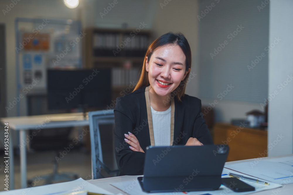 Poster young manager smiling while working late at night in a modern office, using a tablet to stay connect