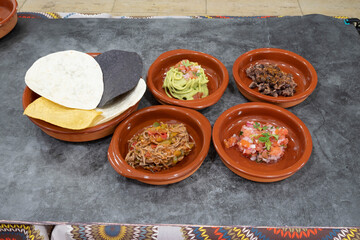 A plate of food with five different dishes on it. The dishes are in small bowls and the plate is on a table