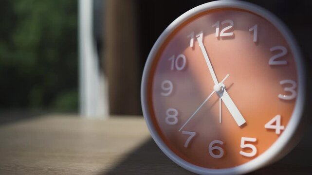 Alarm clock on wooden table over summer morning background