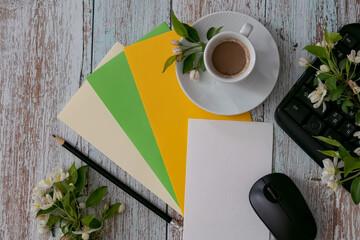 Workspace setup with coffee cup, notebook, pencil, and keyboard on wooden table