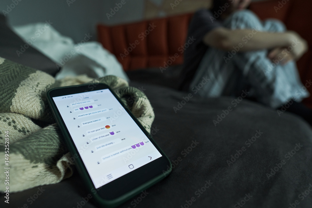 Wall mural image depicting a smartphone on a bed displaying a messaging app, with a person sitting in backgroun
