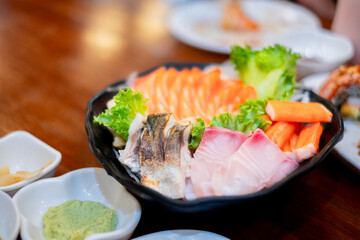 Fresh assorted sashimi platter with salmon, tuna, crab sticks, and wasabi served on a wooden table — perfect for Japanese cuisine and seafood-themed projects