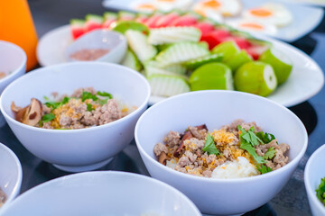 Traditional Thai breakfast with minced pork rice porridge, fresh vegetables, and fried eggs, beautifully served in white bowls and plates on a dining table