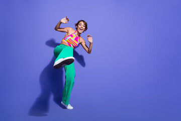 Full length photo of positive nice girl wear trendy clothes have fun dance raised leg empty space isolated on purple color background