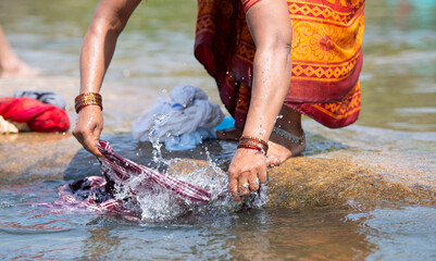 Indian woman washing clothes at Tungabhadra river, Hampi, colorful fabrics, traditional bangles on...
