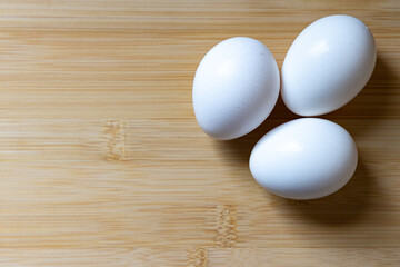 Three fresh eggs on cutting board with copy space