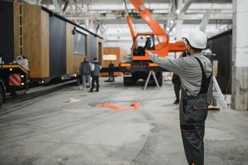 Construction worker directing crane in modular house production workshop