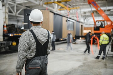 Construction worker supervising prefabricated modular house production in factory