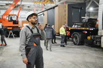 Fototapeta premium Arab engineer communicating with walkie talkie in modular house production workshop