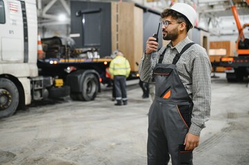 Construction worker communicating with walkie talkie in modular house production workshop