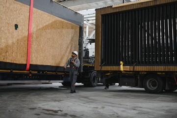 Construction worker supervising modular house transportation in factory