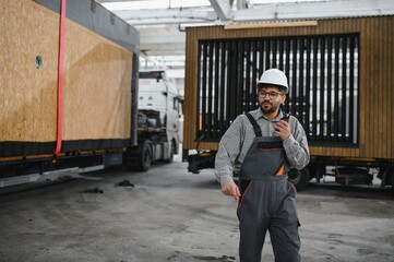Arab construction worker communicating with walkie talkie during modular house production