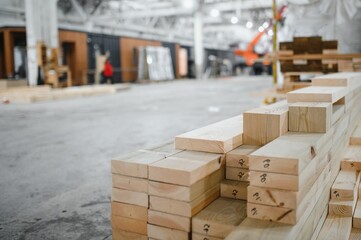 Stack of lumber beams preparing for modular house construction in workshop