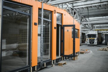 Construction workers building modular orange house in workshop