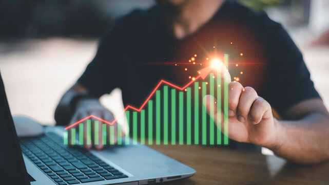 Concept of business growth, financial success, investment strategy, economic forecast, and data analytics.Businessman analyzing stock market chart with growth bar graph and arrow trend.
