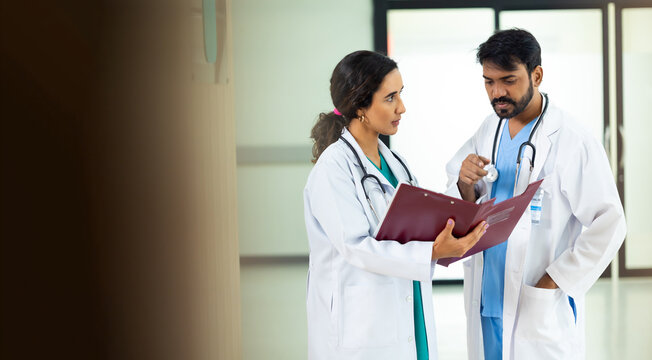 teamwork concept : Two professional doctors meeting discussing diagnosis, checking test results in clinic. Medical staff, healthcare. Diverse people Indian and hispanic latin doctor