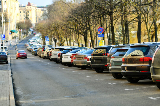 Urban traffic problem with rows of cars parked in tight angle along the street, congestion and lack of parking space. Angle parking along the edge of city street with cars squeezed into every spot