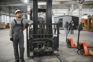 Arab construction worker leaning on forklift in modular house factory