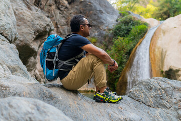 Hiker resting and admiring waterfall in puebla, mexico