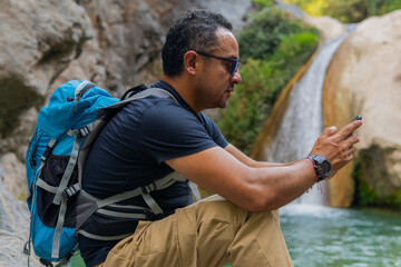 Tourist using smartphone near waterfall in puebla, mexico