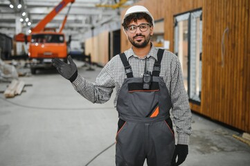 Arab construction worker gesturing in modular house production workshop