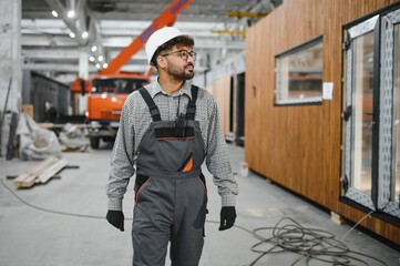 Arab construction worker inspecting prefabricated modular house in workshop