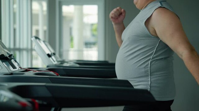middle-aged fat man is running on a treadmill in a gym to lose weight and be healthy.