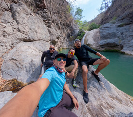 Four male hikers taking a selfie near a waterfall in a rocky canyon