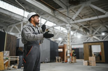 Arab construction worker communicating with walkie talkie in modular house factory