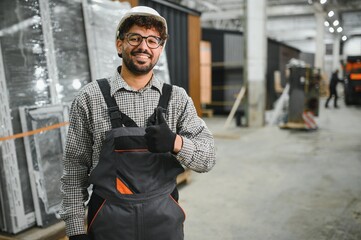 Arab construction worker gesturing thumbs up in modular house production workshop