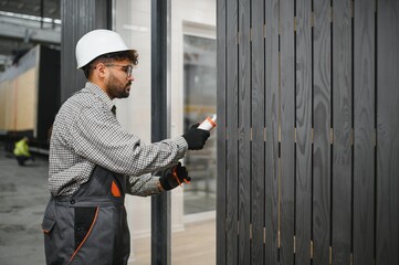 Construction worker applying sealant to prefabricated modular house wall