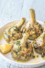 Four Roman-style artichokes served on white plate, tender and beautifully seasoned