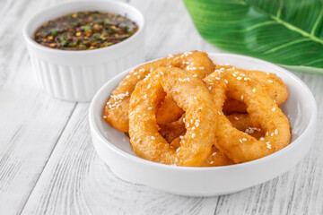 Crispy battered calamari rings with sesame seeds and spicy Asian dipping sauce