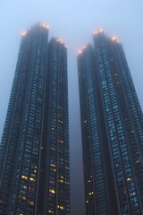 Obraz premium Foggy Skyscraper View, Tall Buildings with Warm Glowing Windows at Dusk Urban