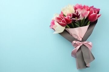 Obraz premium Bouquet of beautiful tulips on light blue background, top view. Space for text
