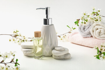 Spa products, pebble stones and twigs with beautiful flowers on white table, closeup