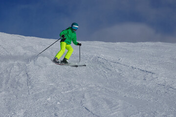 Skier teenage boy leans forward to carve down the snowy slope