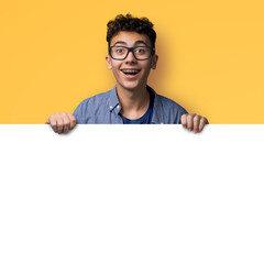 Image of happy man wear glasses, braces stand behind blank empty banner mockup sign board signboard, advertise show pointing area for slogan text isolate yellow background. Dental care ad