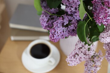 Bouquet of beautiful lilac flowers and coffee on wooden table, closeup
