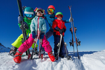 Family of happy skiers with kids pose happily on snowy slopes