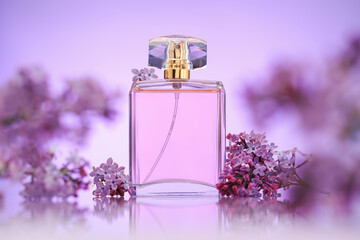 Bottle of perfume and lilac flowers on mirror surface against violet gradient background, selective...