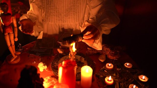 Mystical ritual with burning candles, tarot cards, and a person s hands performing a spiritual ceremony in low light ambiance.