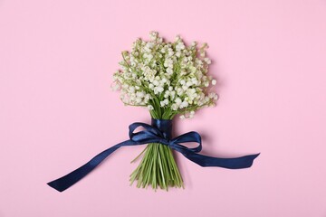 Beautiful lily-of-the-valley flowers on light pink background, top view
